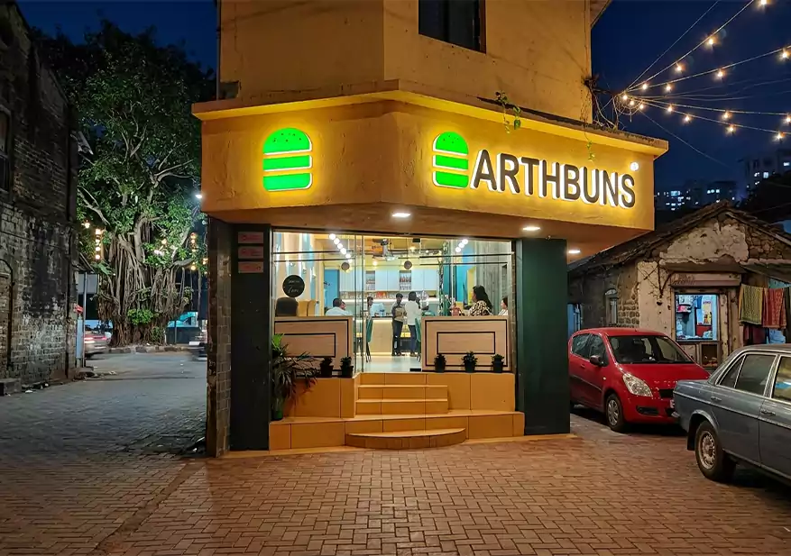 Cafe storefront exterior with illuminated EarthBuns signage and glass entrance.
