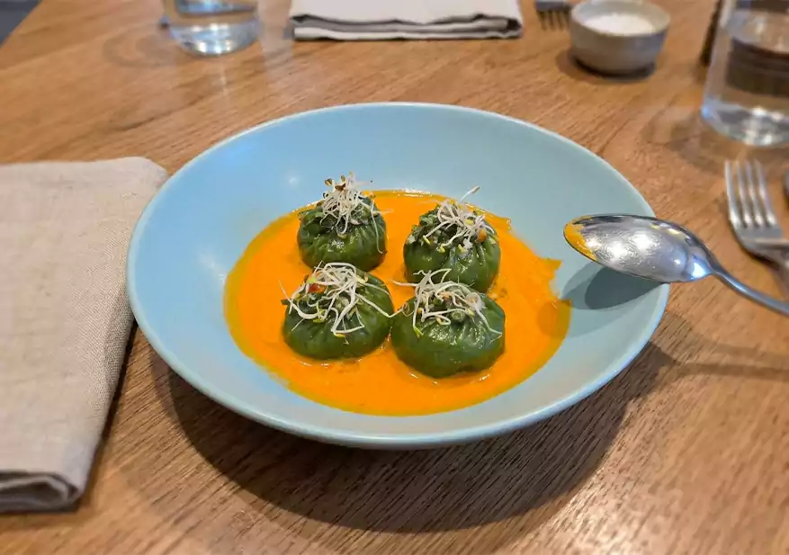 Four green vegetable dim sums served over orange sauce