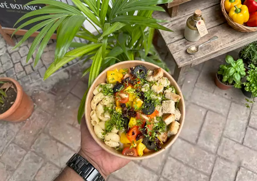 Pasta salad bowl with black olives, chopped bell peppers, and diced tomatoes