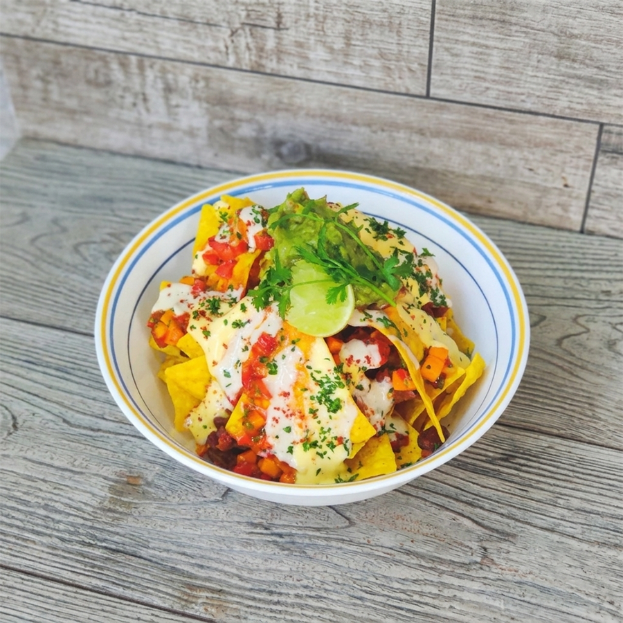 Bowl of crispy nachos topped with guacamole, melted cheese, and fresh salsa