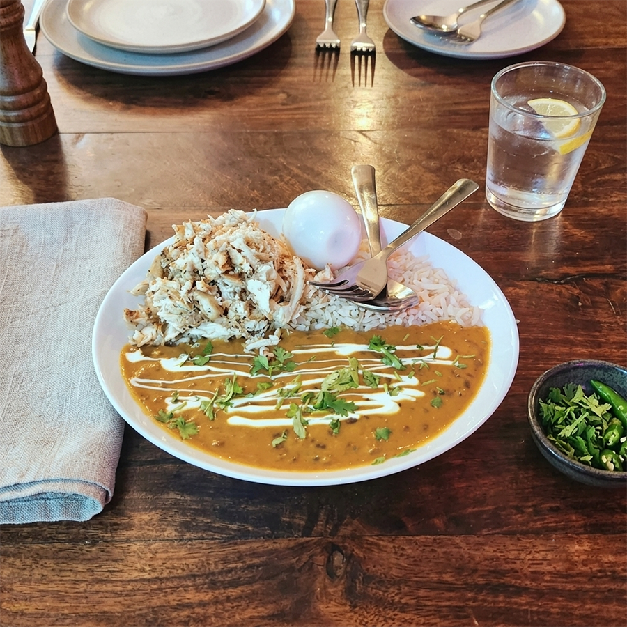 Nutritious protein and rice bowl garnished with fresh herbs and a cream drizzle.