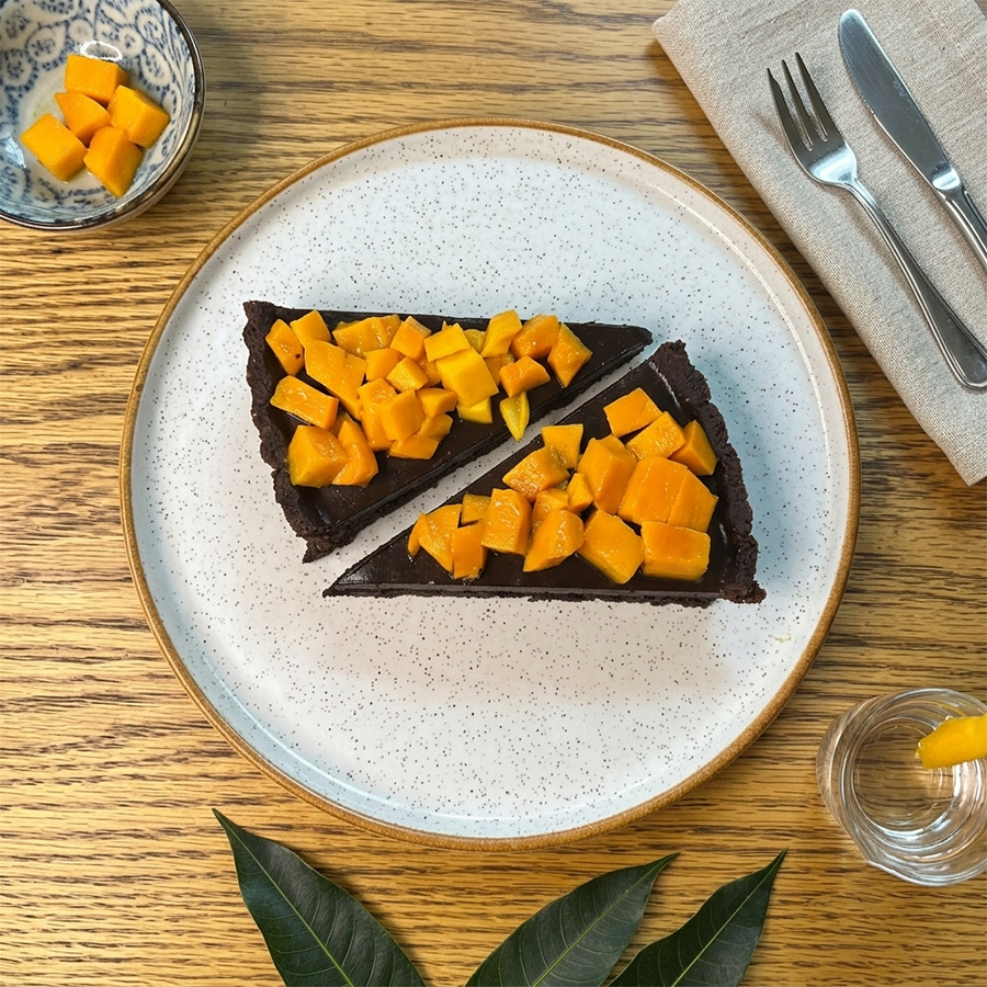 Vegan dark chocolate tart topped with fresh mango pieces